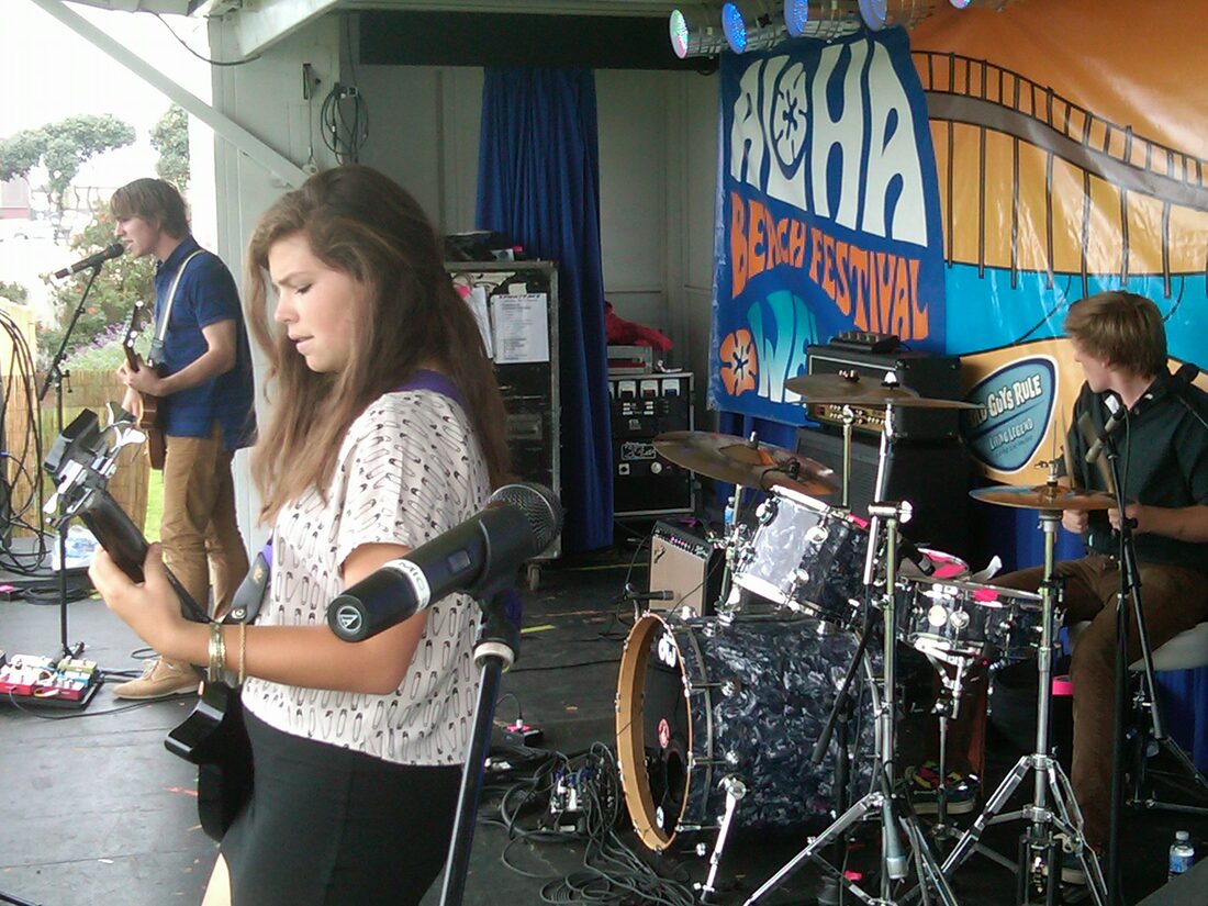 Musician performing on the Main Stage beneath the Aloha Beach Festival banner