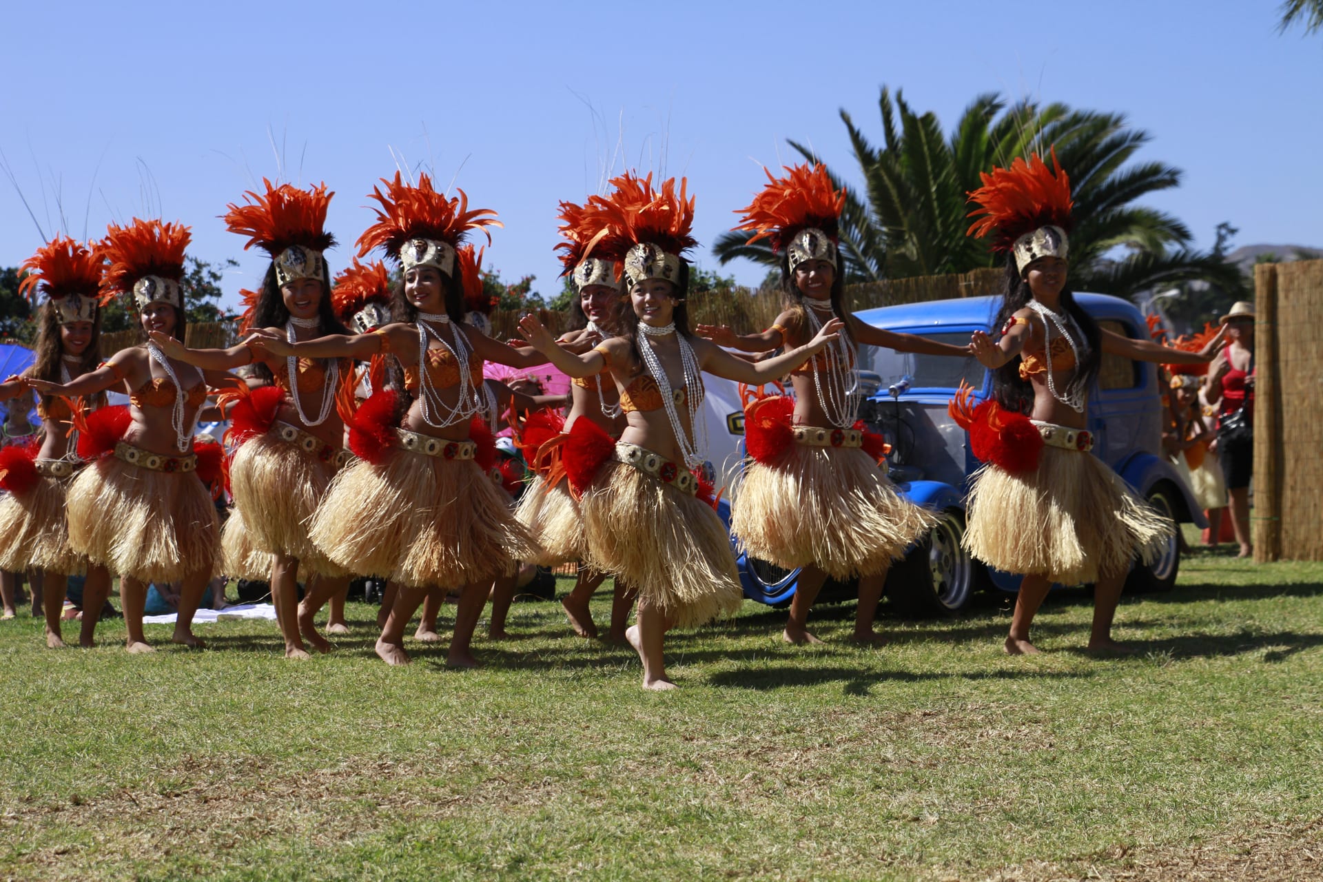 Troupe in red feather headdresses dancing on the lawn