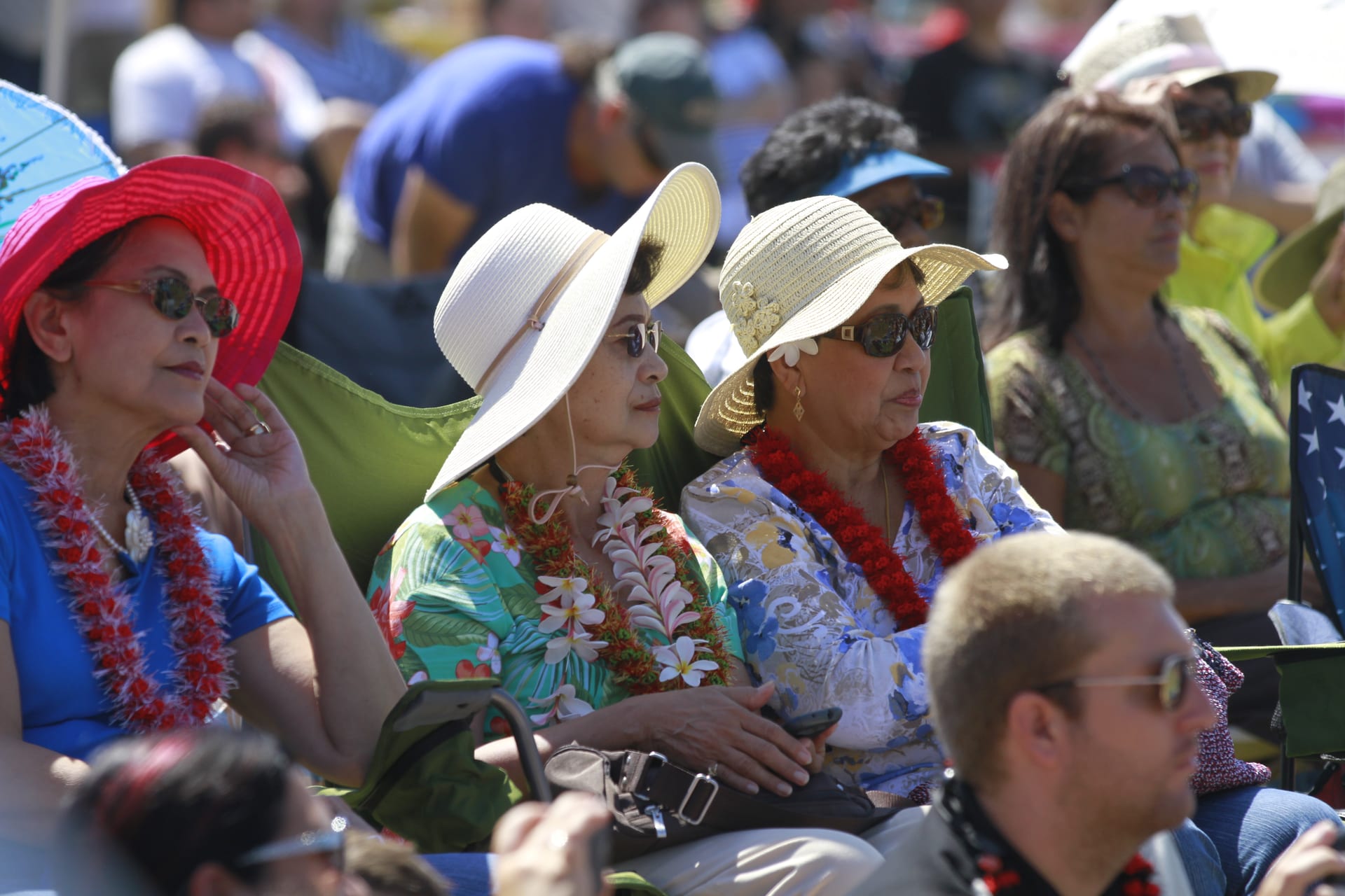 Audience members wearing leis and sun hats watching a Main Stage performance